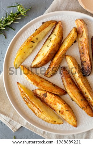 Homemade Rosemary Potato Wedges on a plate, top view. Flat lay, overhead, from above. 