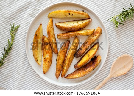 Homemade Rosemary Potato Wedges on a plate, overhead view. Flat lay, top view, from above.