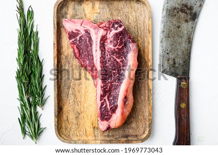 Dry aged Raw T bone or porterhouse marbled beef meat Steak with herbs and spices set, on white stone background, top view flat lay
