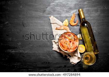 botella de vino blanco con camarón y limón. En el pizarrón negro.