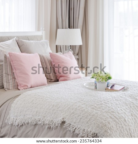 pink pillows on bed with white tray of flower at home