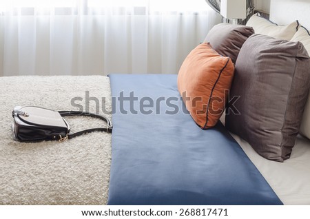 modern bedroom with colorful pillows and female\'s bag on bed at home
