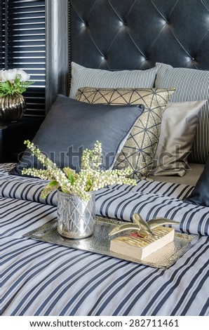 tray of book with vase of  plant on bed in luxury black bedroom at home