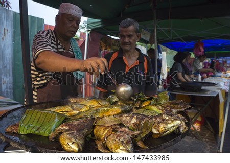 KUALA LUMPUR - JULY 25: Unidentified man sell grilled fish at traditional iftar market during Ramadan at Taman Sri Rampai, near Kuala Lumpur, Malaysia on July 25, 2013.