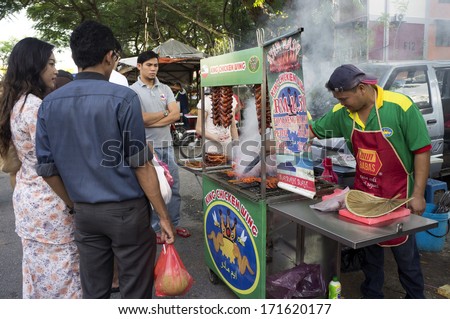 KUALA LUMPUR - JULY 11: Unidentified street food vendor, sale the grilled chicken wing to his customers during iftar at Wangsamaju, Kuala Lumpur, Malaysia on July 11, 2013