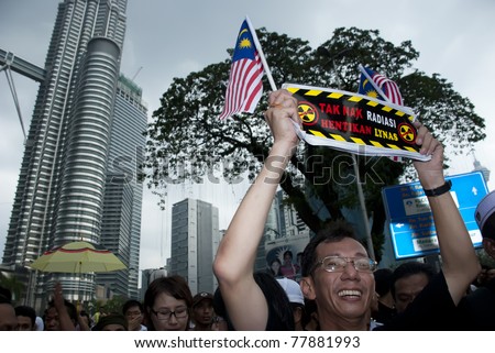 KUALA LUMPUR, MALAYSIA-MAY 20: An activist holds a poster during a protest against a proposed rare earth plant to be built in Gebeng, in front of Petronas Twin Towers in Kuala Lumpur May 20, 2011.
