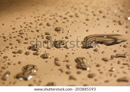 Pattern of water drops in a shiny metallic surface with table reflections