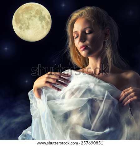 Half-naked girl wrapped in translucent white cloth moves in the light of the full moon