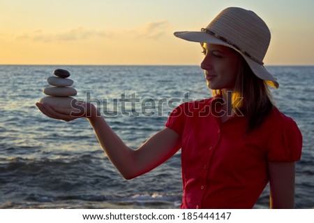 Young woman against the sea with stones in her hand