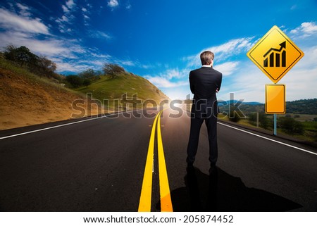 businessman standing in front of a sign with a chart on a windy road