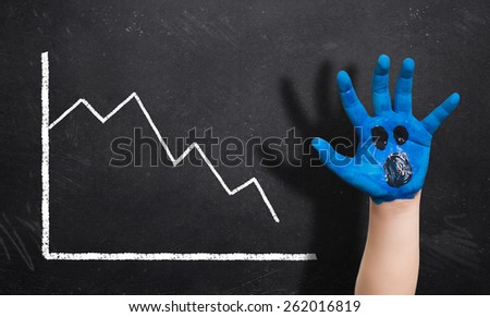 decreasing chart on a blackboard and a painted hand with a scared expression in front of it