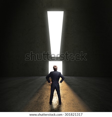 businessman standing in front of a portal shaped as a exclamation mark