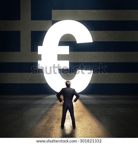 businessman standing in front of a portal shaped as Euro in a wall painted with the greek flag