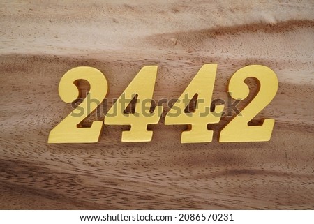Golden Arabic numerals 2442 on a dark brown to white wood grain background. Foto stock © 