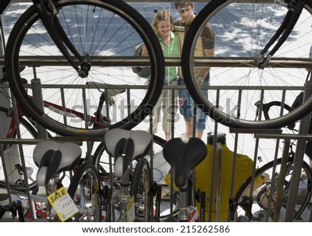 Young couple looking at new bikes in bicycle shop window display, focus on background, elevated view
