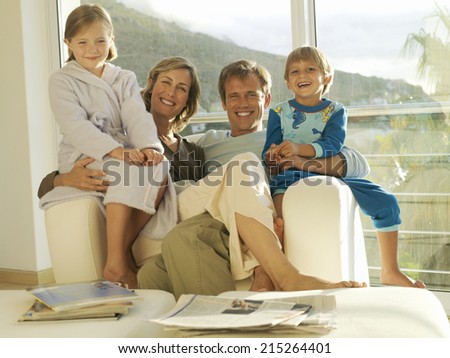 Two generation family relaxing in armchair beside balcony sliding doors, smiling, portrait