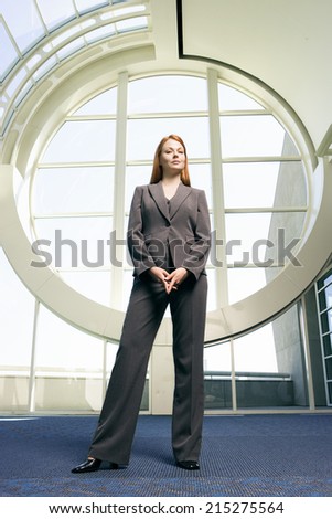 Confident businesswoman, with ginger hair, wearing grey suit, smiling, front view, portrait (surface level)