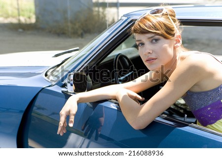 Young woman leaning on open door of car, portrait, close-up
