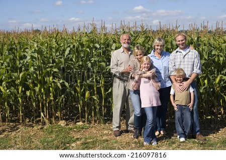 Family of three generations by corn field, smiling, portrait