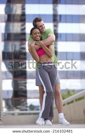 Young couple in exercise clothes, man embracing woman