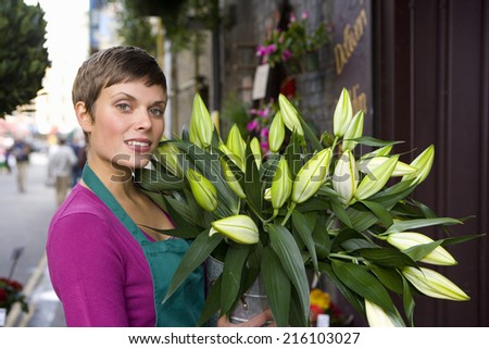 Female florist with bunch of flowers, smiling, portrait