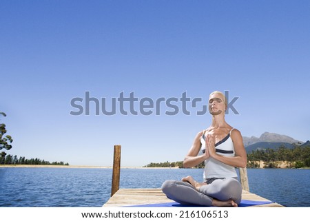 Woman meditating on lake dock