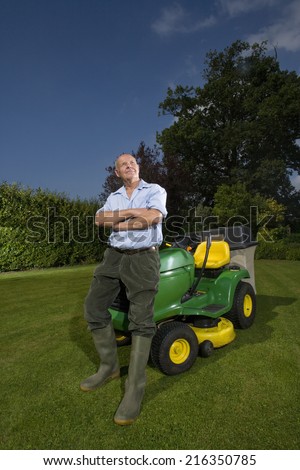 Senior man leaning on riding lawn mower