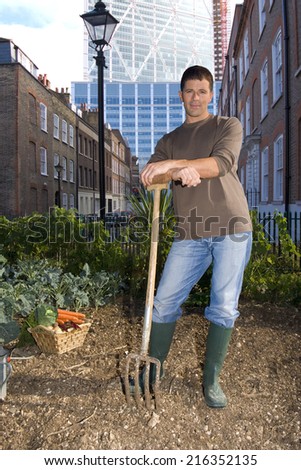 Man posing with pitchfork in urban rooftop garden