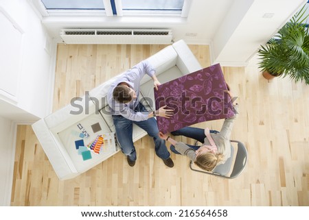 Couple looking at wallpaper sample in living room