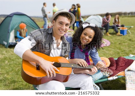 Couple with guitar camping and attending outdoor festival