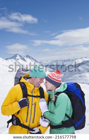 Couple with backpacks smiling face to face on snowy mountain