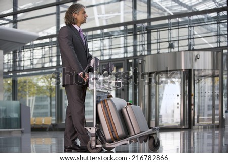 A businessman standing at the airport with his luggage.