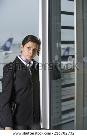 A businesswoman leaning on a door at the airport.