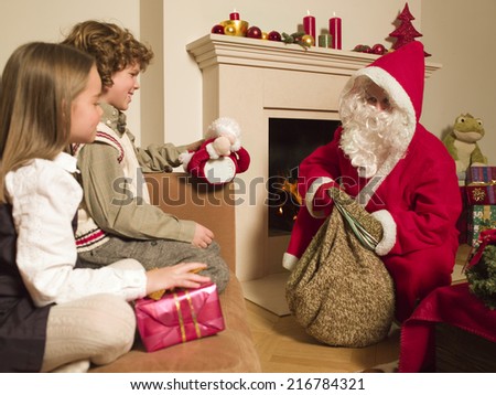 Man dressed as Santa giving gifts to children.