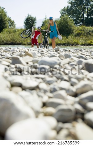 A couple walking with their cycles.