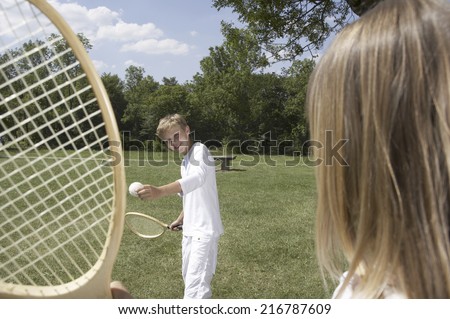 A boy playing tennis in a park.