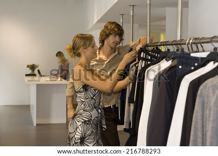 A couple looking at clothes in a boutique.