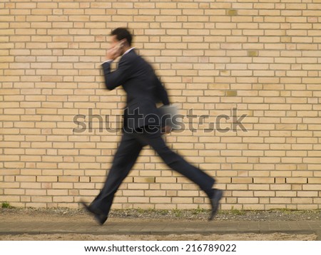 A businessman running and talking on his mobile phone.