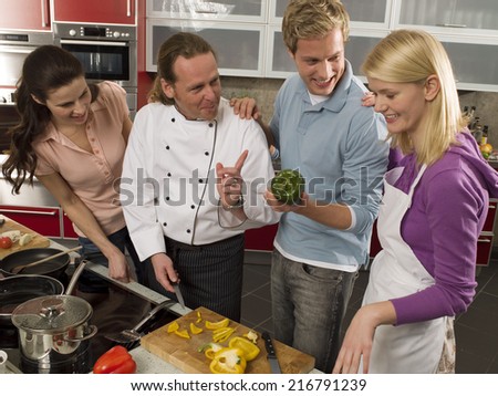 Male chef teaching three students in the kitchen
