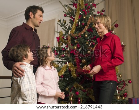 A family standing around the Christmas tree.