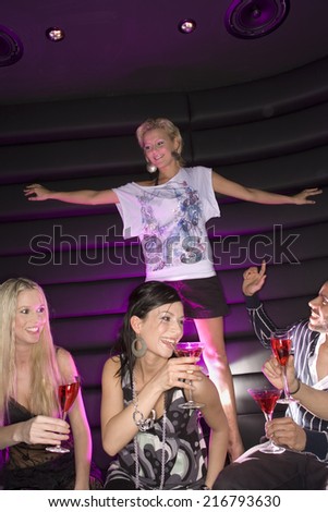 Young woman dancing in a nightclub with her friends having drinks