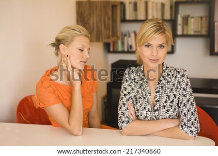 Portrait of a young woman grinning with another young woman sitting beside her