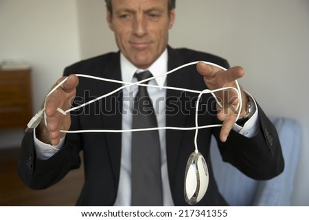 Mature man tangled in a computer mouse wire