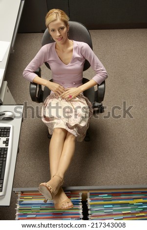 Young woman sitting in an office chair with her legs on a filing cabinet drawer
