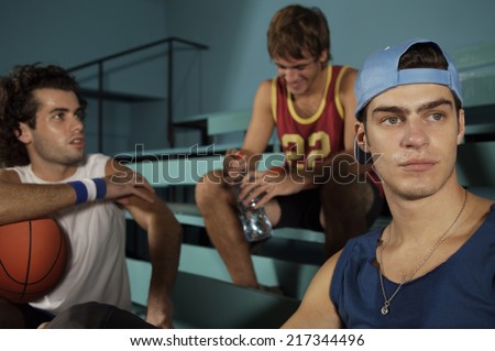 Three young men sitting in a basketball court