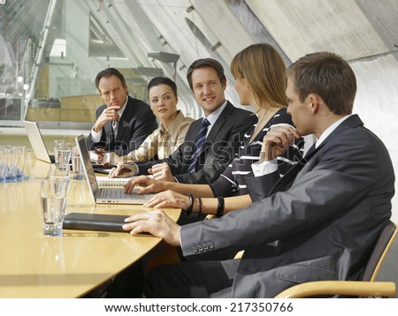 Five business executives sitting and discussing in a board room