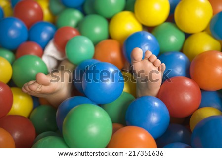 Close-up of a child\'s feet in a ball pool