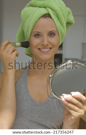 Woman with make-up brush and hand mirror