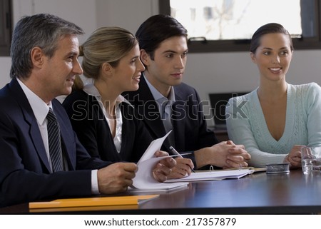 Four business executives sitting at a conference table in a conference room