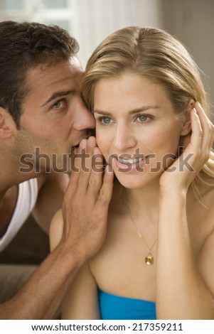 Close-up of a young man whispering to a young woman